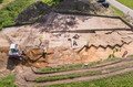 Ein Bagger trägt den Mutterboden für archäologische Untersuchungen ab – die Feinarbeit erfolgt per Hand von den Archäologen.