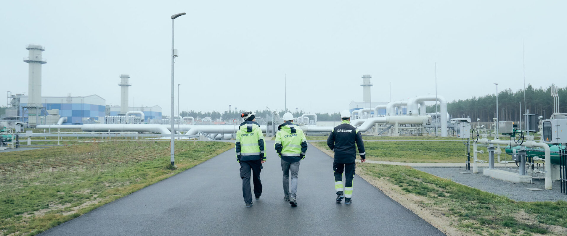 Three employees walking to a compressor station